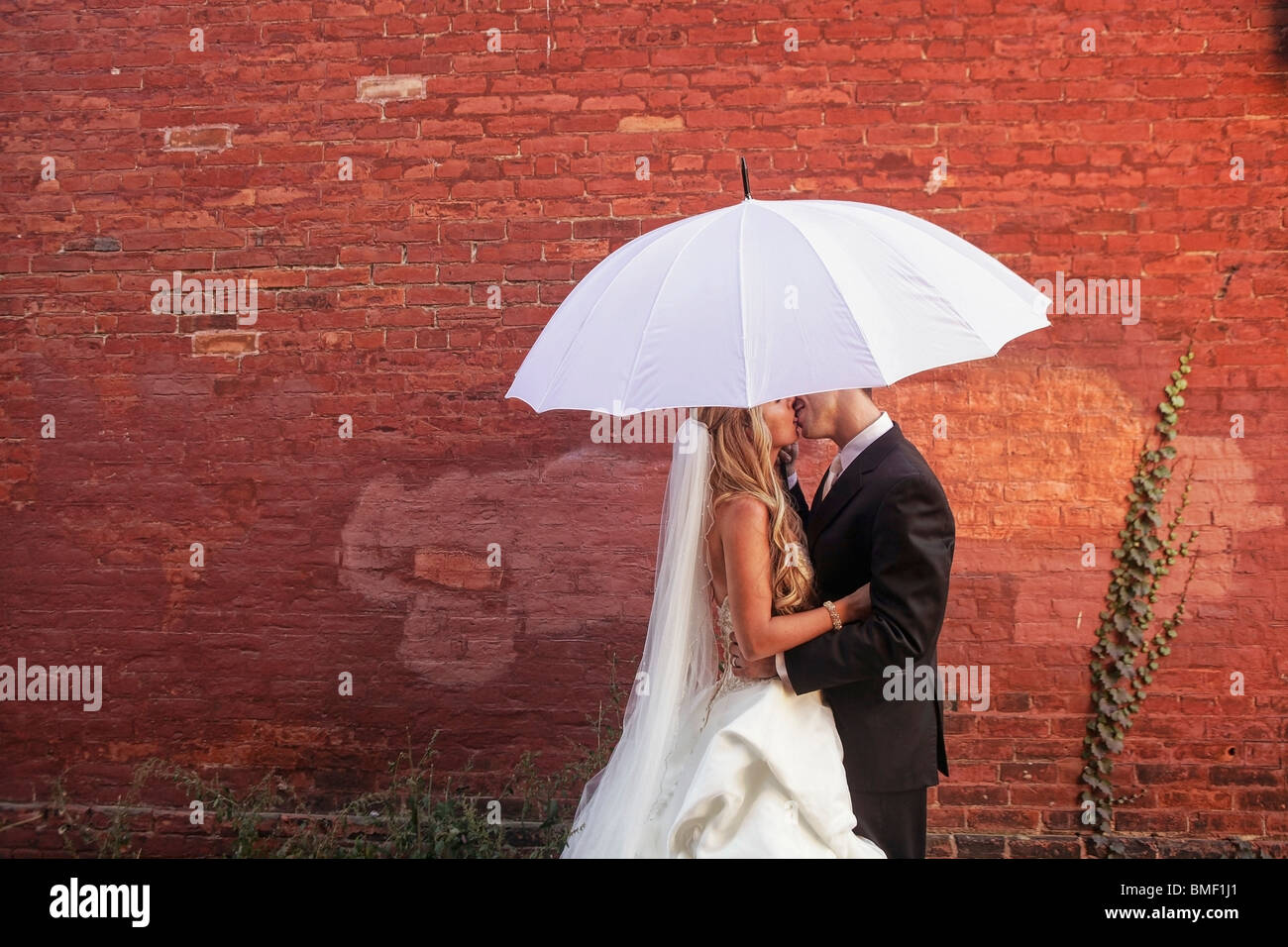 A Bride And Groom Under A White Umbrella Stock Photo