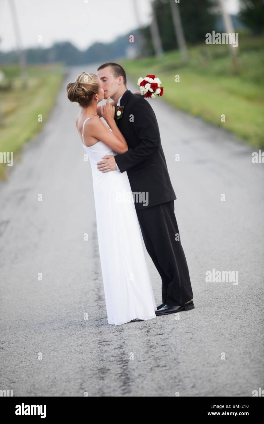 A Bride And Groom Kissing In The Middle Of The Road Stock Photo - Alamy