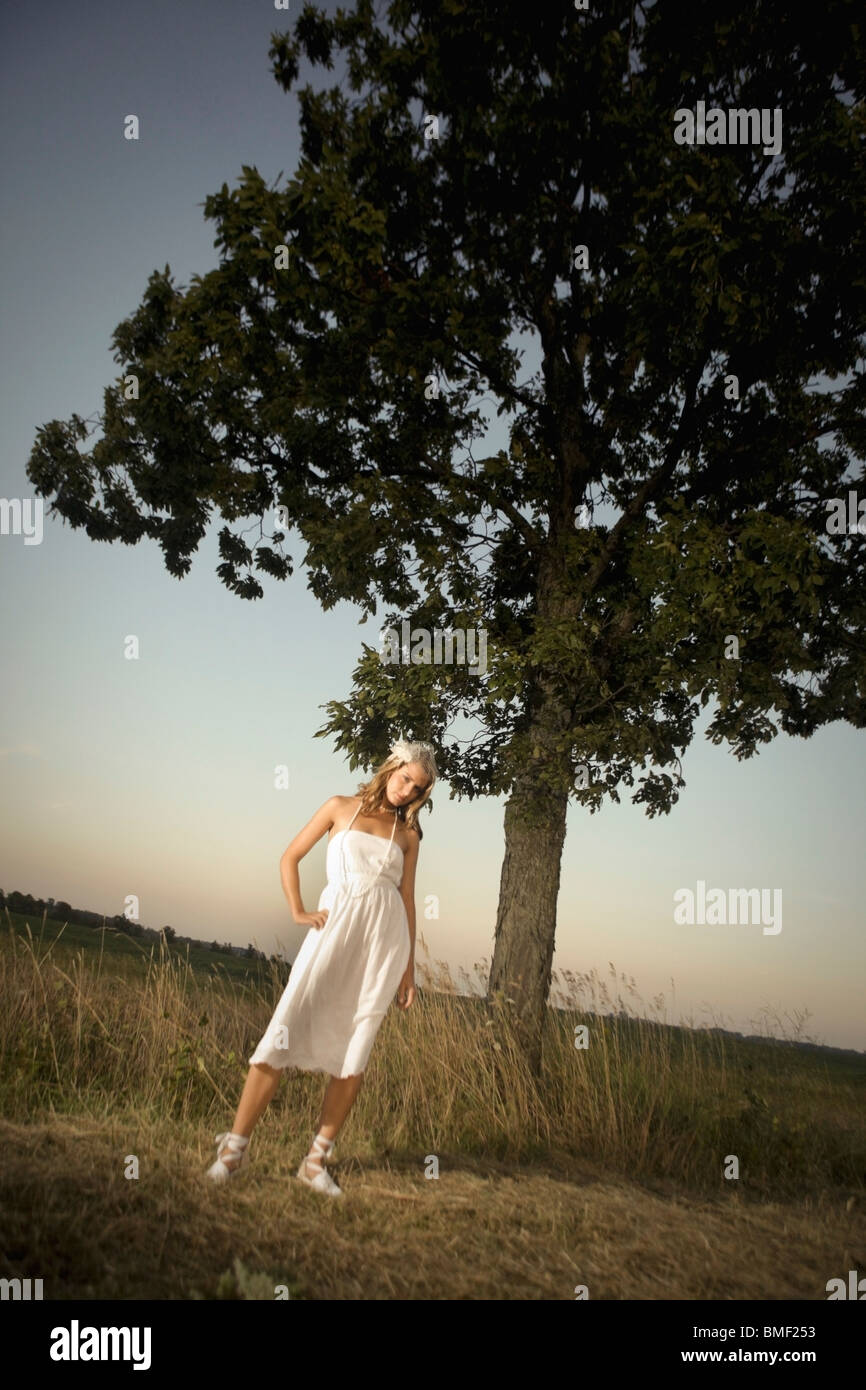 A Bride Standing Under A Tree In A Field Stock Photo