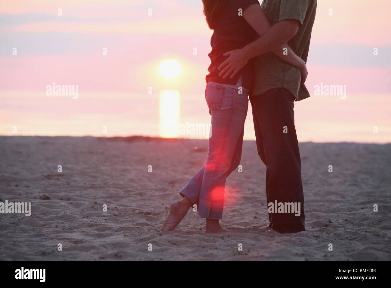 A Couple Standing Together On A Beach At Sunset Stock Photo