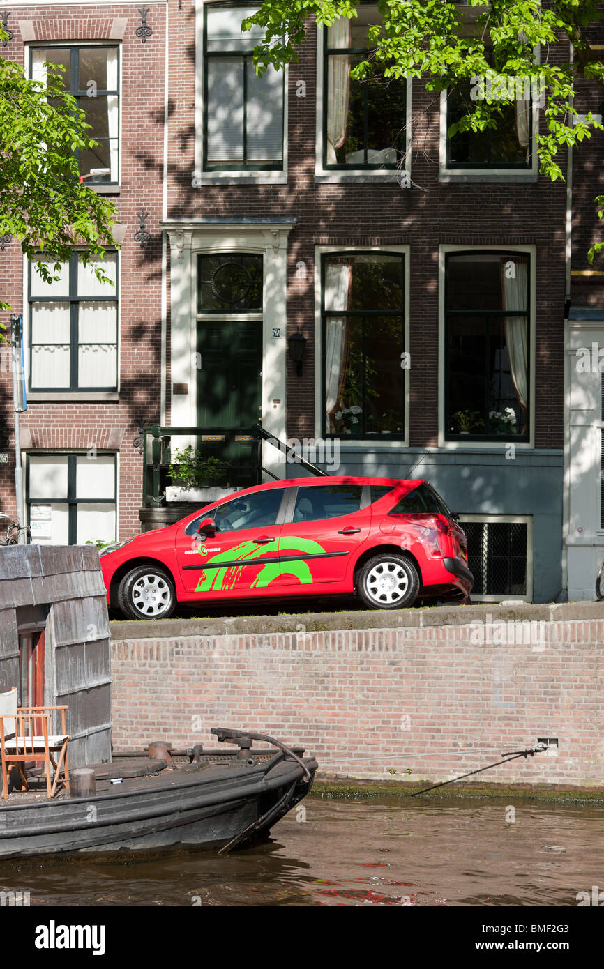 A Green Wheels car for car sharing, dating, short term rental, on a canal in Amsterdam. Peugeot 207. Stock Photo