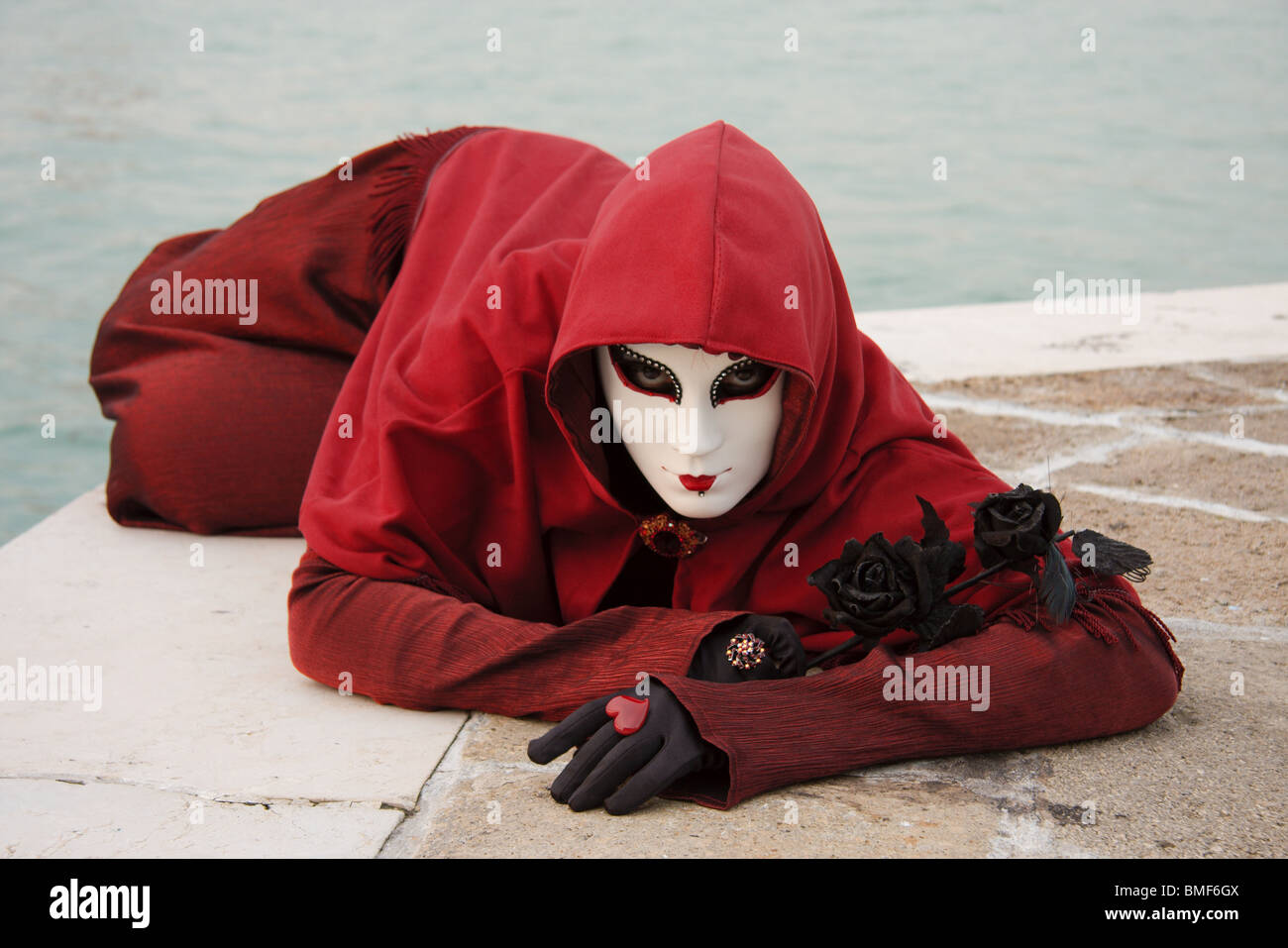 Woman in "Red Riding Hood" Cloak and Dress with Black Rose and Gloves, with  Canal background, at Venice Carnevale Stock Photo - Alamy
