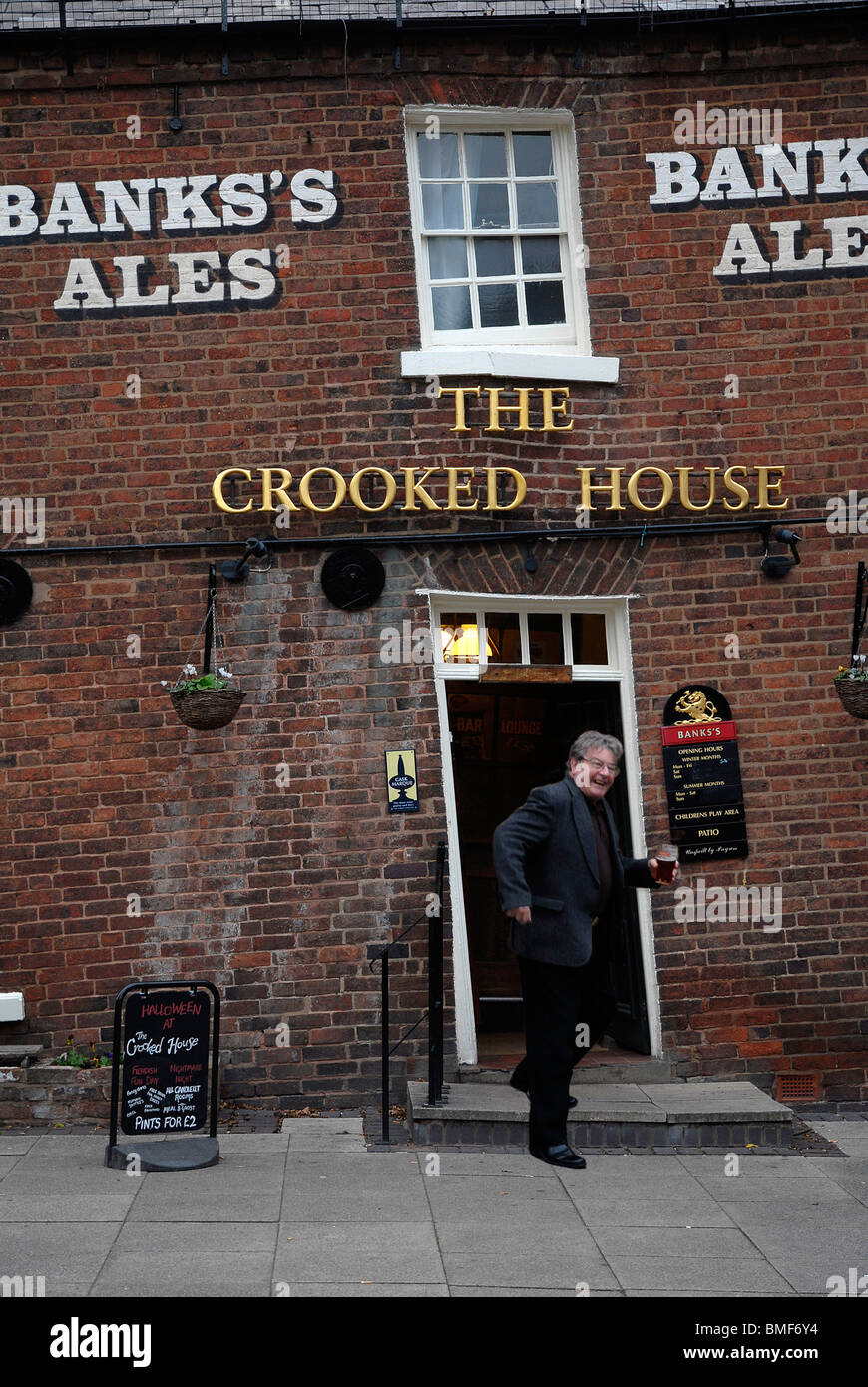 A customer heads for the beer garden the Crooked House Pub in Himley, Gornal Wood, West Midlands Stock Photo