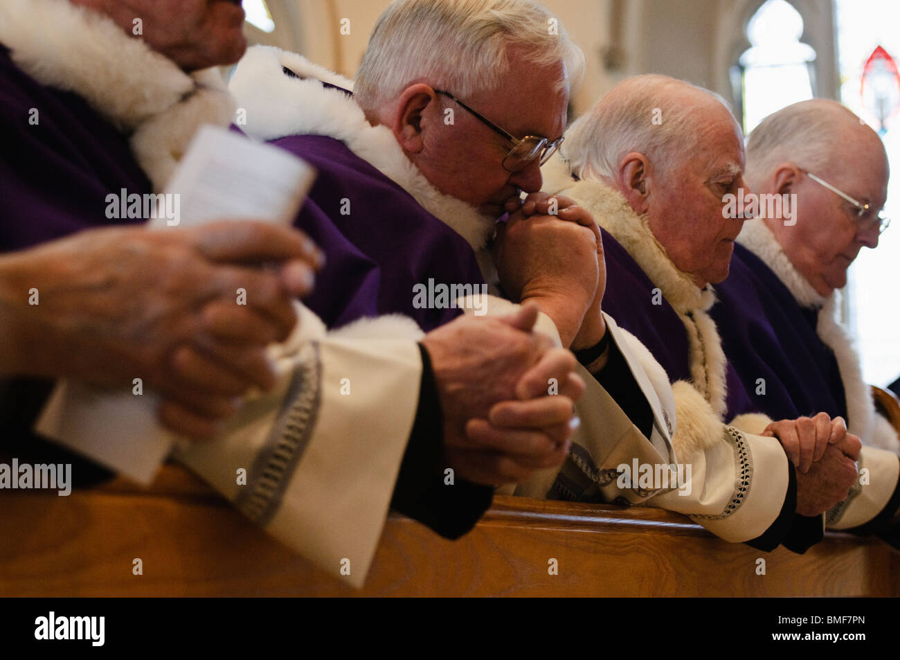 Priests kneeling and praying in church pews at requiem mass for Cardinal Cahal Daly Stock Photo