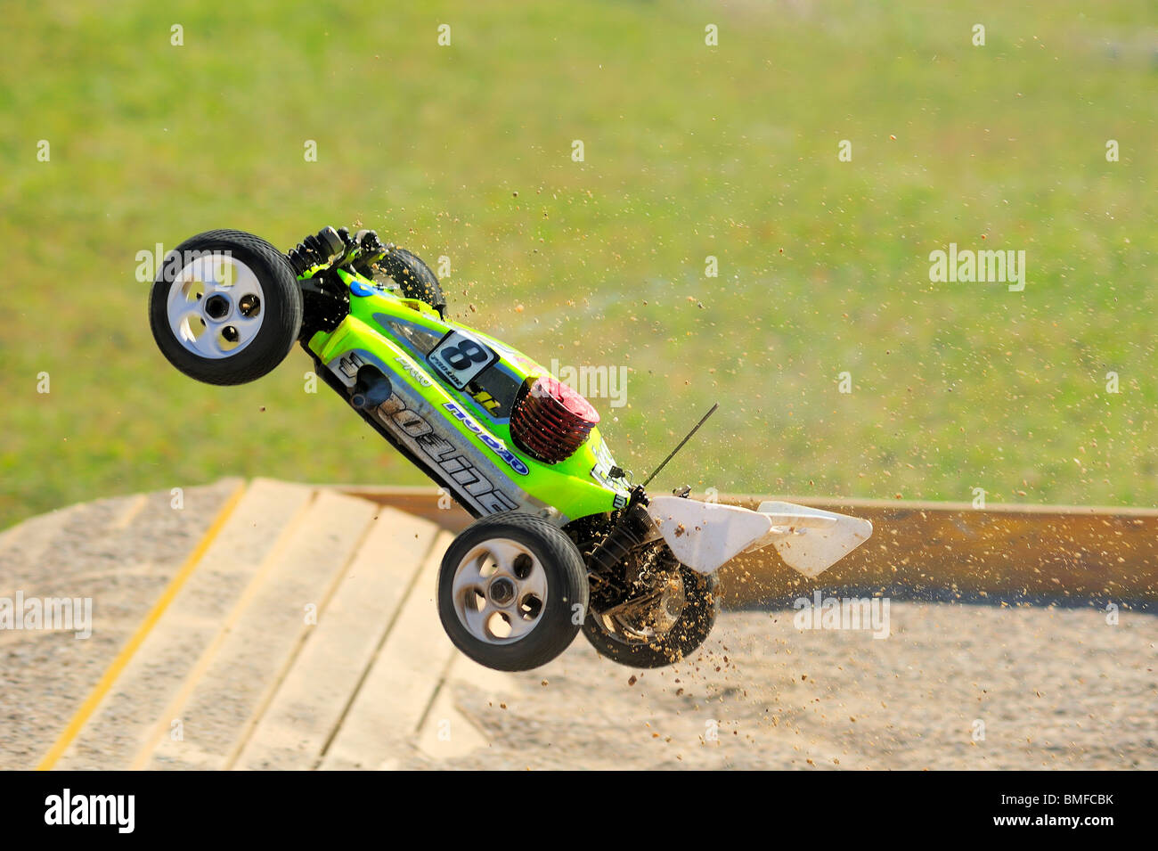 A radiocontrolled model racing car in midair at a jump during a race