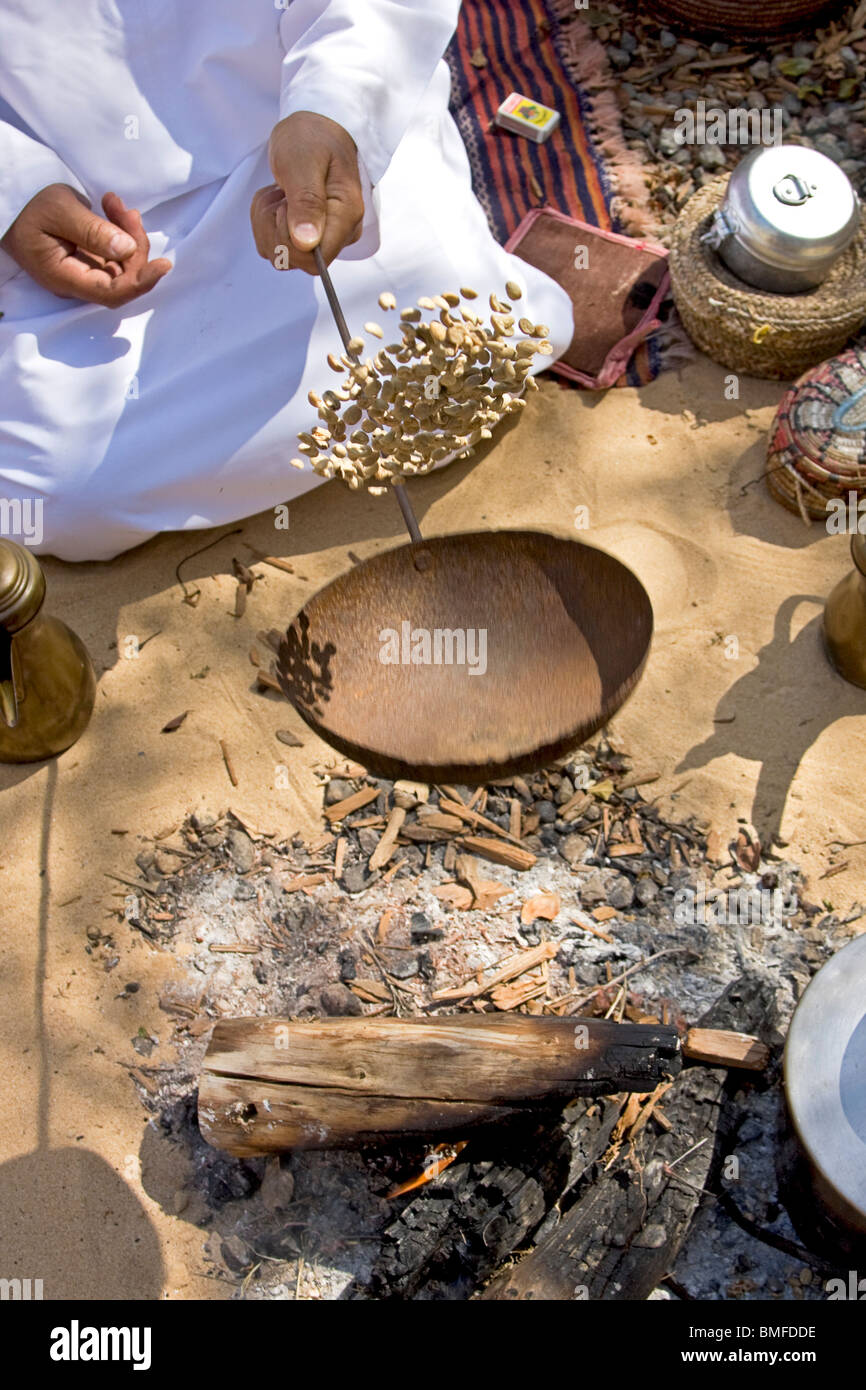 Typical Arab Arab man in typical Arab dress shows how coffee was roasted before ...