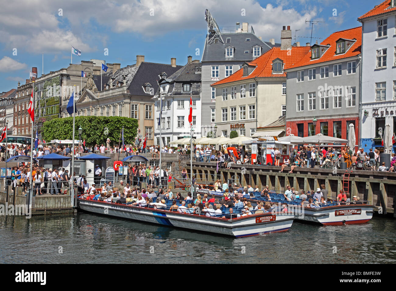 Boarding jetty for the canal cruises leaving Nyhavn in Copenhagen on sightseeing tours just below the many waterside restaurants Stock Photo