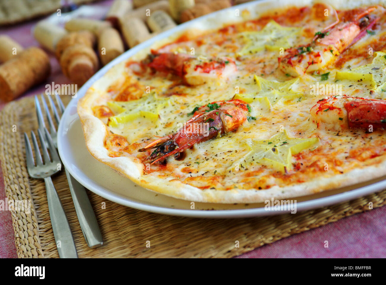 Table set with a tasty italian pizza of shrimps and carambola star-fruit Stock Photo