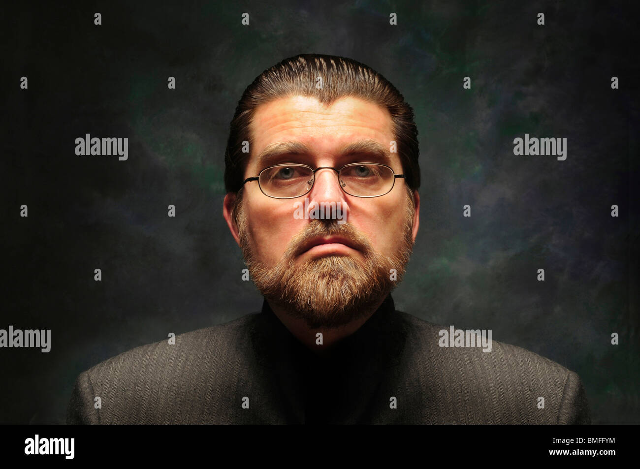 Orwellian character with glasses and beard against a dark mottled background Stock Photo