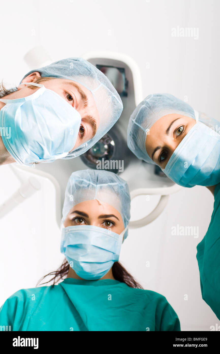 Team of medical professionals looking down at patient in surgical ...