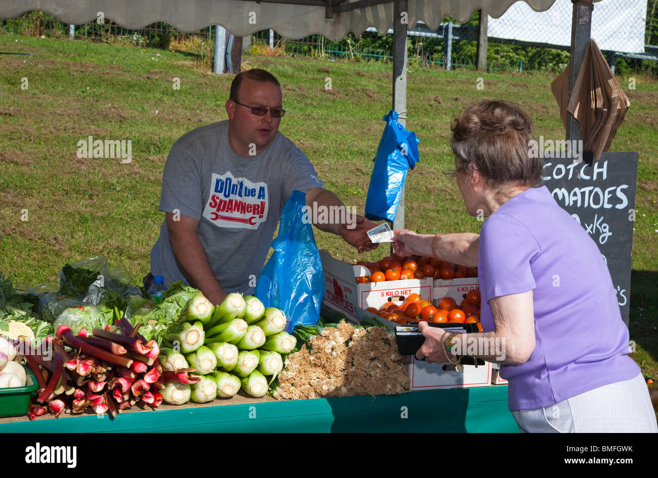 Woman buying fresh fruit and vegetables from a stall holder at a farmer