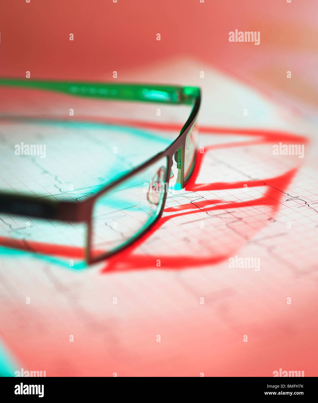 Glasses lying on ECG results casting a shadow with subtle blue and red lighting Stock Photo