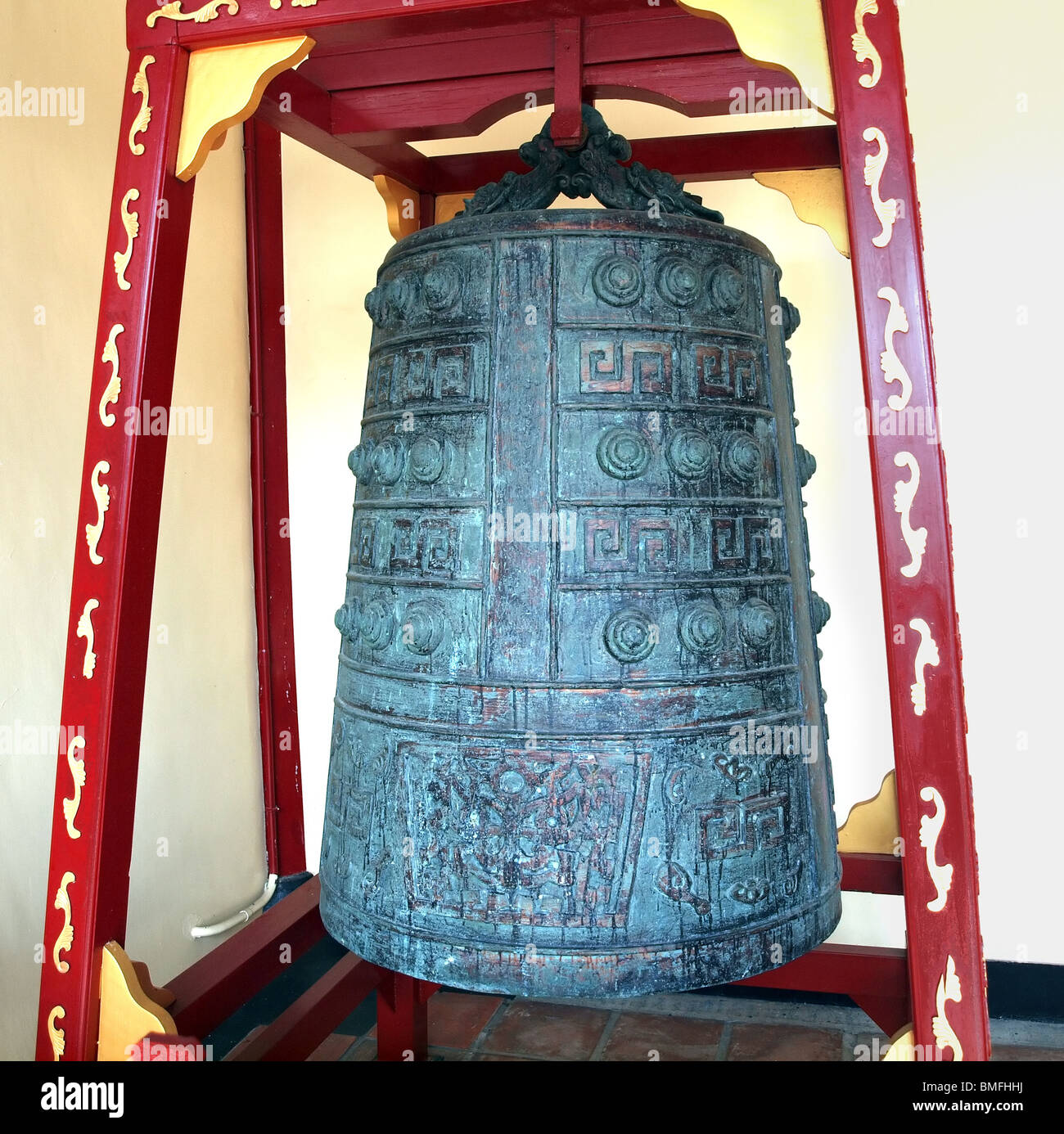 A large Chinese temple bell is suspended from a wooden frame Stock