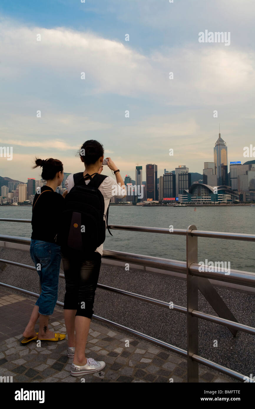 Two women take photos of Victoria Harbour, Wan Chai, Hong Kong, China