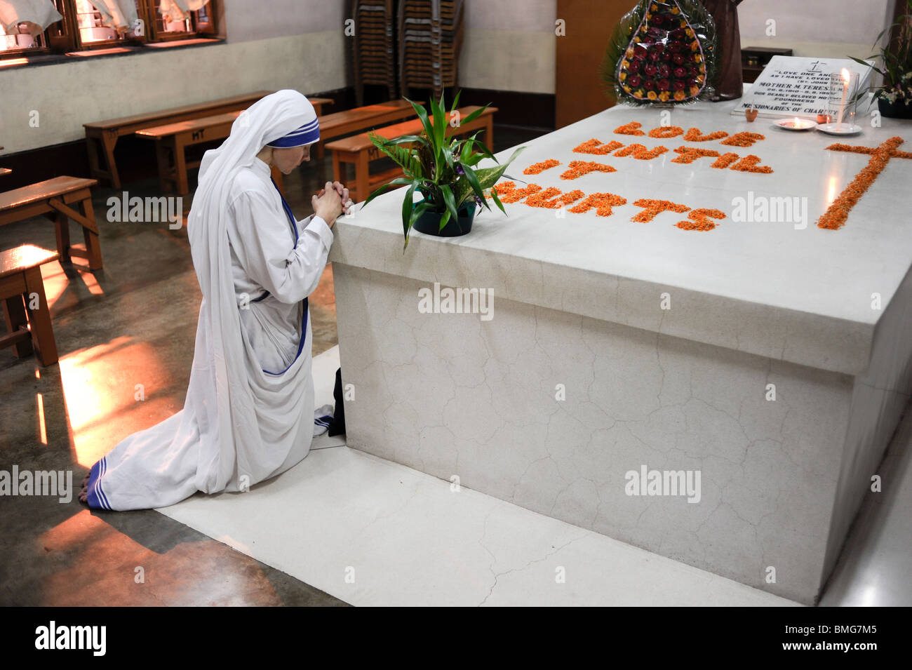 India Kolkata Calcutta, nun praying at grave of Mother Teresa at Mother ´s Teresa house, written with flowers Love until it hurts Stock Photo