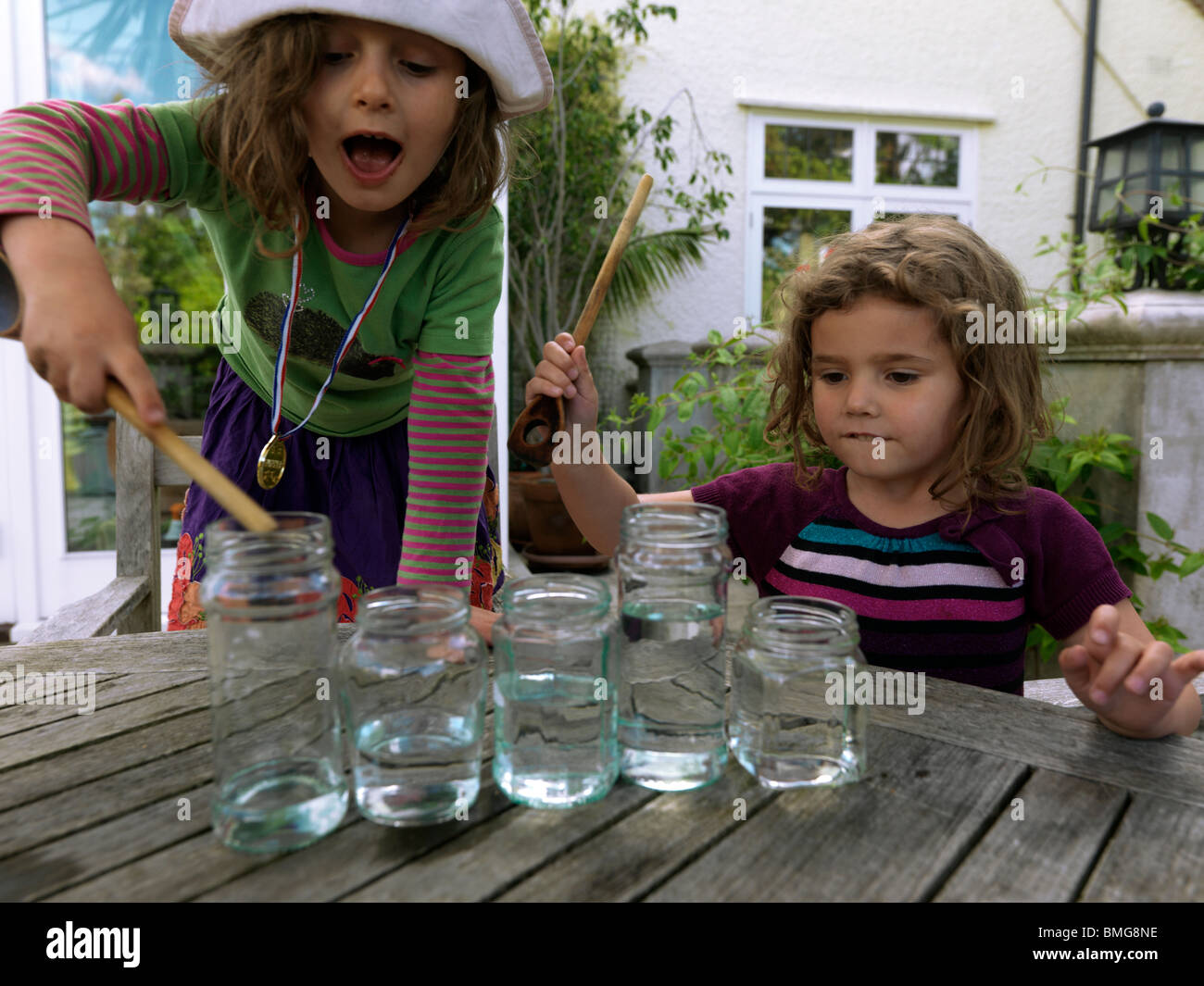 Girls Making Music Using Glass Jars Full Of Water And Hitting Them With ...