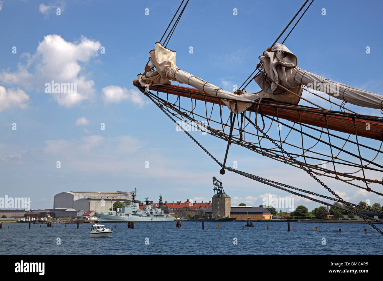 View of the port of Copenhagen towards the old naval station Holmen with the historic rigging sheers (mast crane) and a warship. Stock Photo