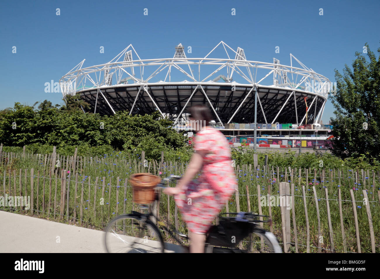 A cyclist on the Greenway passes the partly constructed London 2012 Olympic Athletics Stadium in Stratford, London. (June 2010) Stock Photo