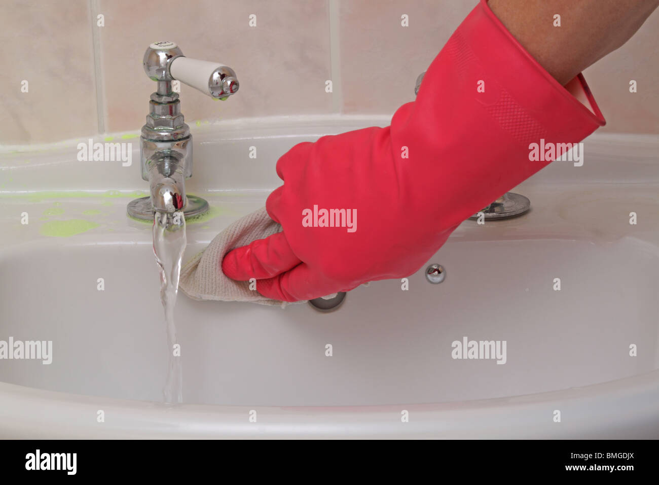 man wearing rubber gloves while cleaning the bathroom sink Stock Photo