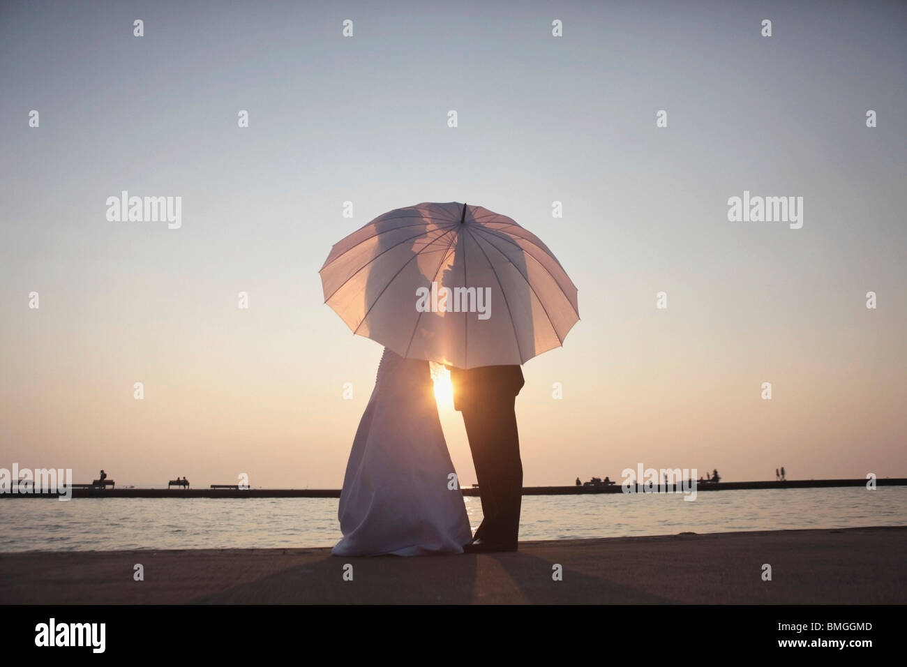 Silhouette Of A Bride And Groom Behind An Umbrella Stock Photo