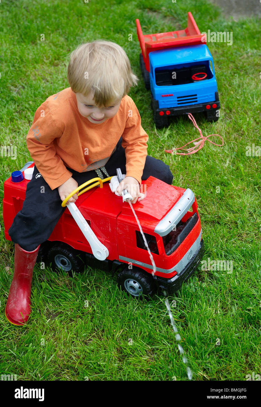 Boy With Toy Fire Engine on garden lawn Stock Photo
