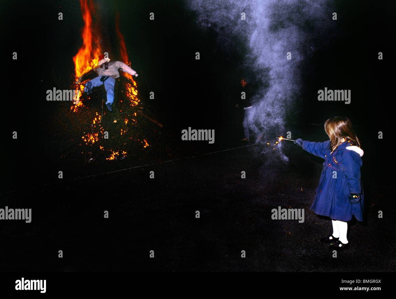 Guy Fawkes Guy On Top Of Lighted Bonfire Watched By Child Stock Photo