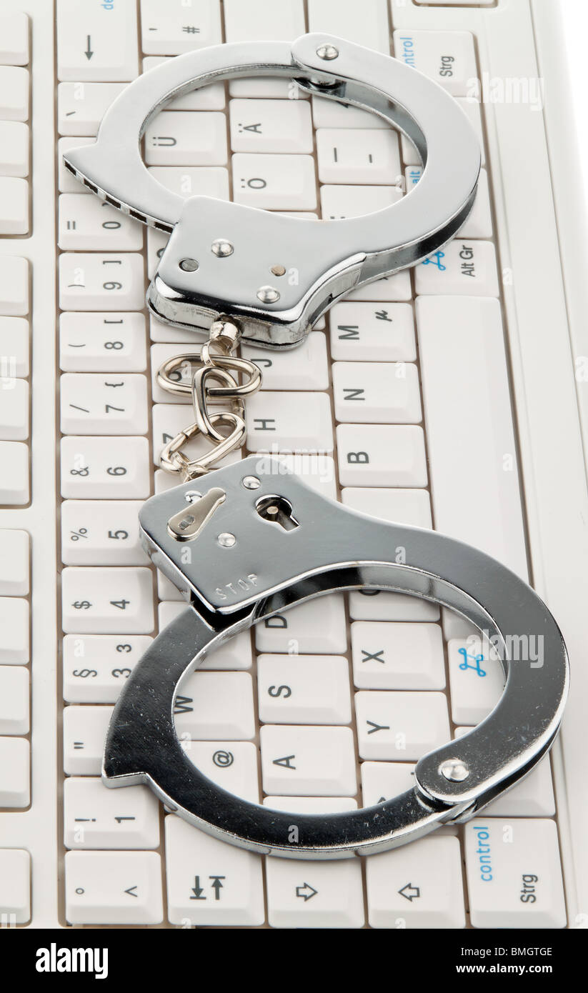 A computer keyboard and handcuffs. Cybercrime. Stock Photo