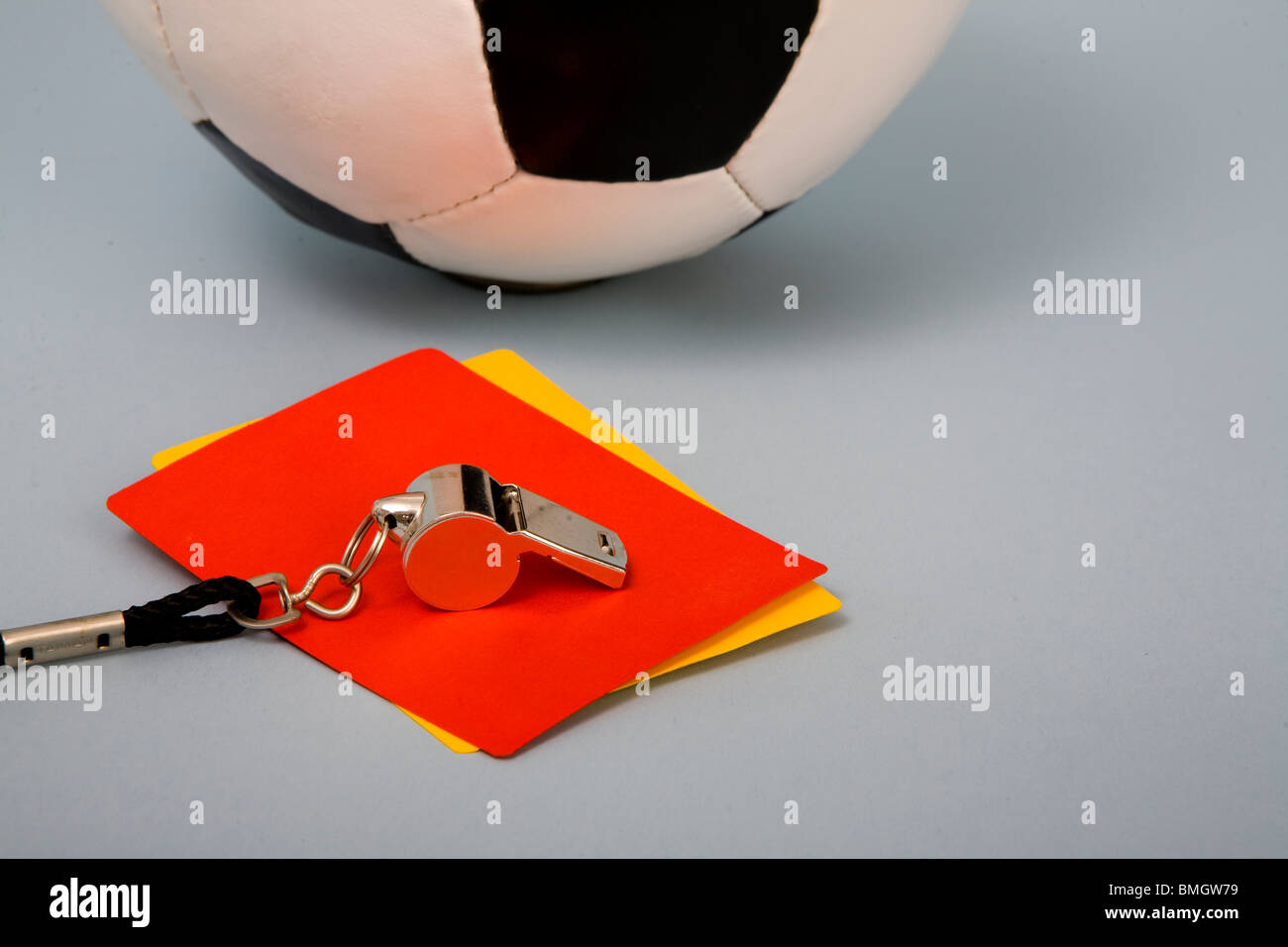 Black white leather football behind whistle and yellow and red card Stock Photo