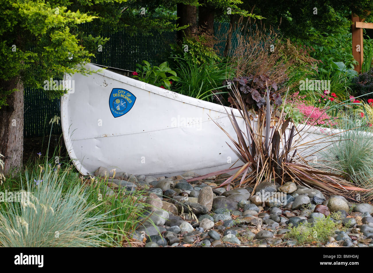Canoe planter filled with plants is part of a charming garden corner welcoming you to Des Moines, Washington. Stock Photo