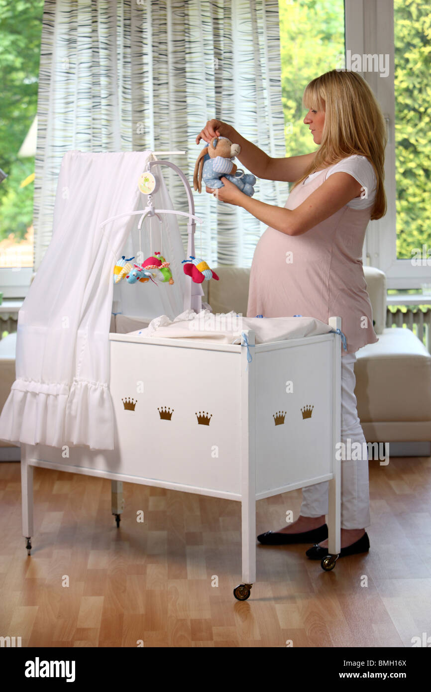 Pregnant, young woman is preparing a baby cradle at home Stock Photo