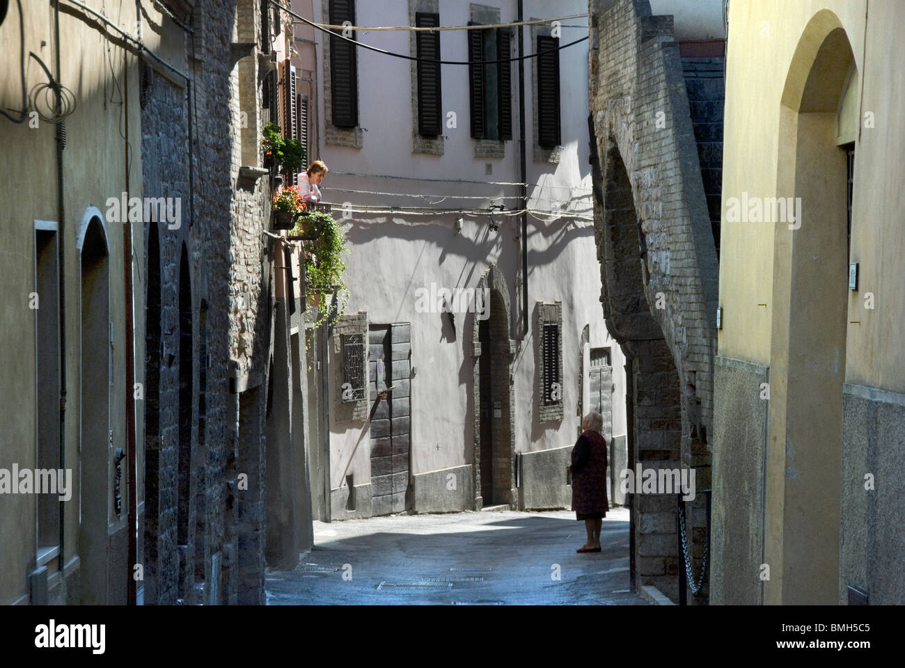 Two women in conversation from the window to the street in the town of Spello, Umbria, Italy Stock Photo