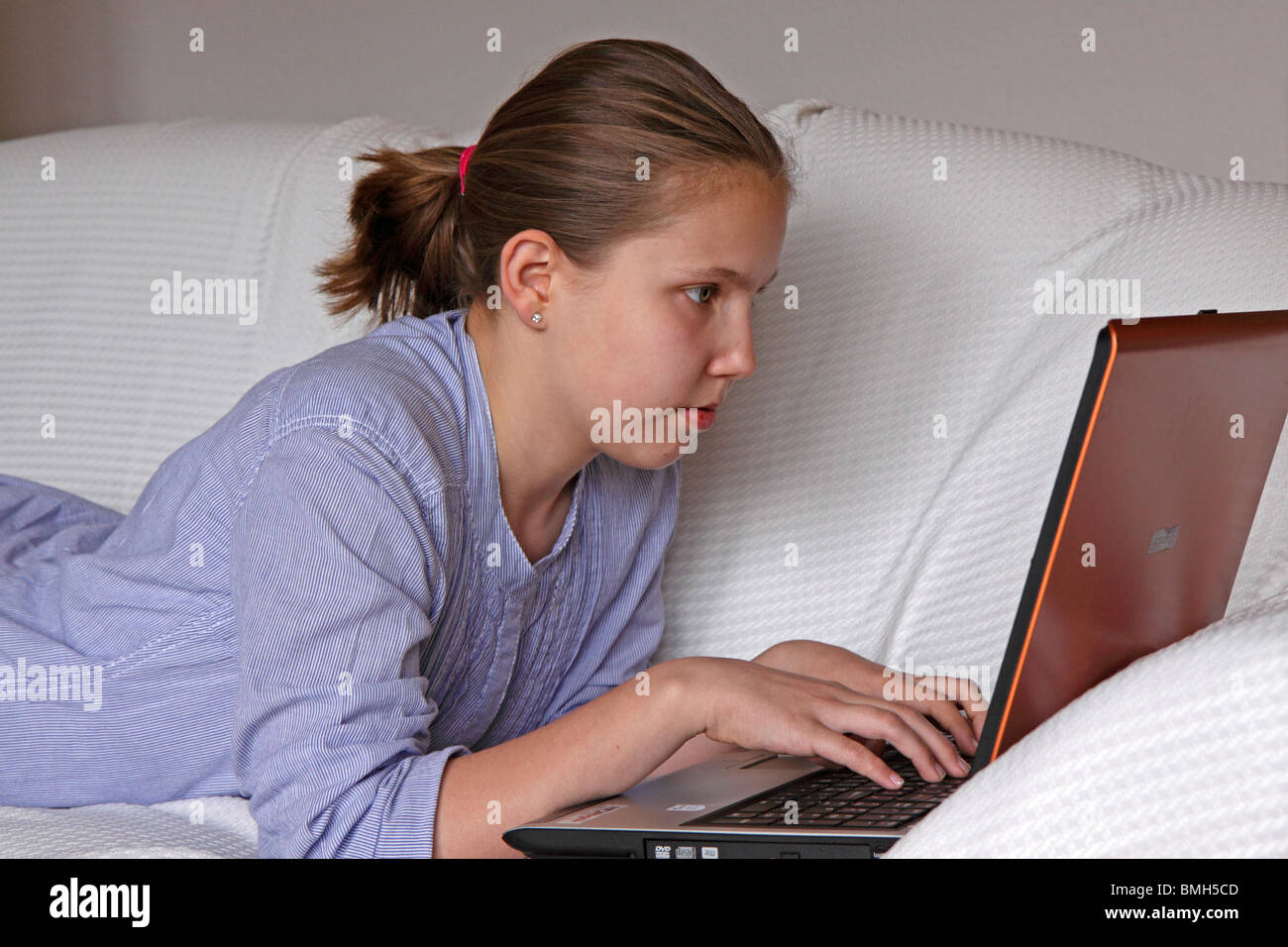 portrait of a young girl lying on a couch with her laptop Stock Photo ...