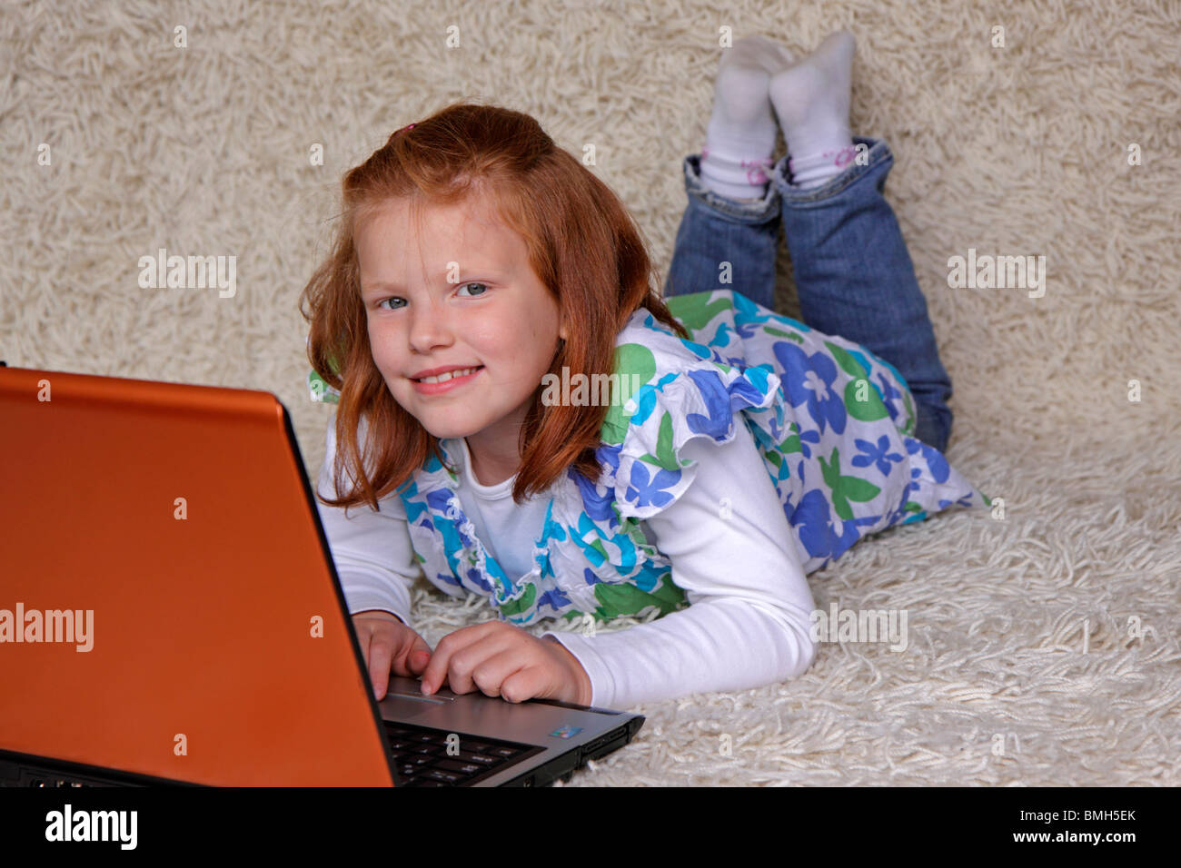 portrait of a young girl lying on the floor with her laptop Stock Photo ...