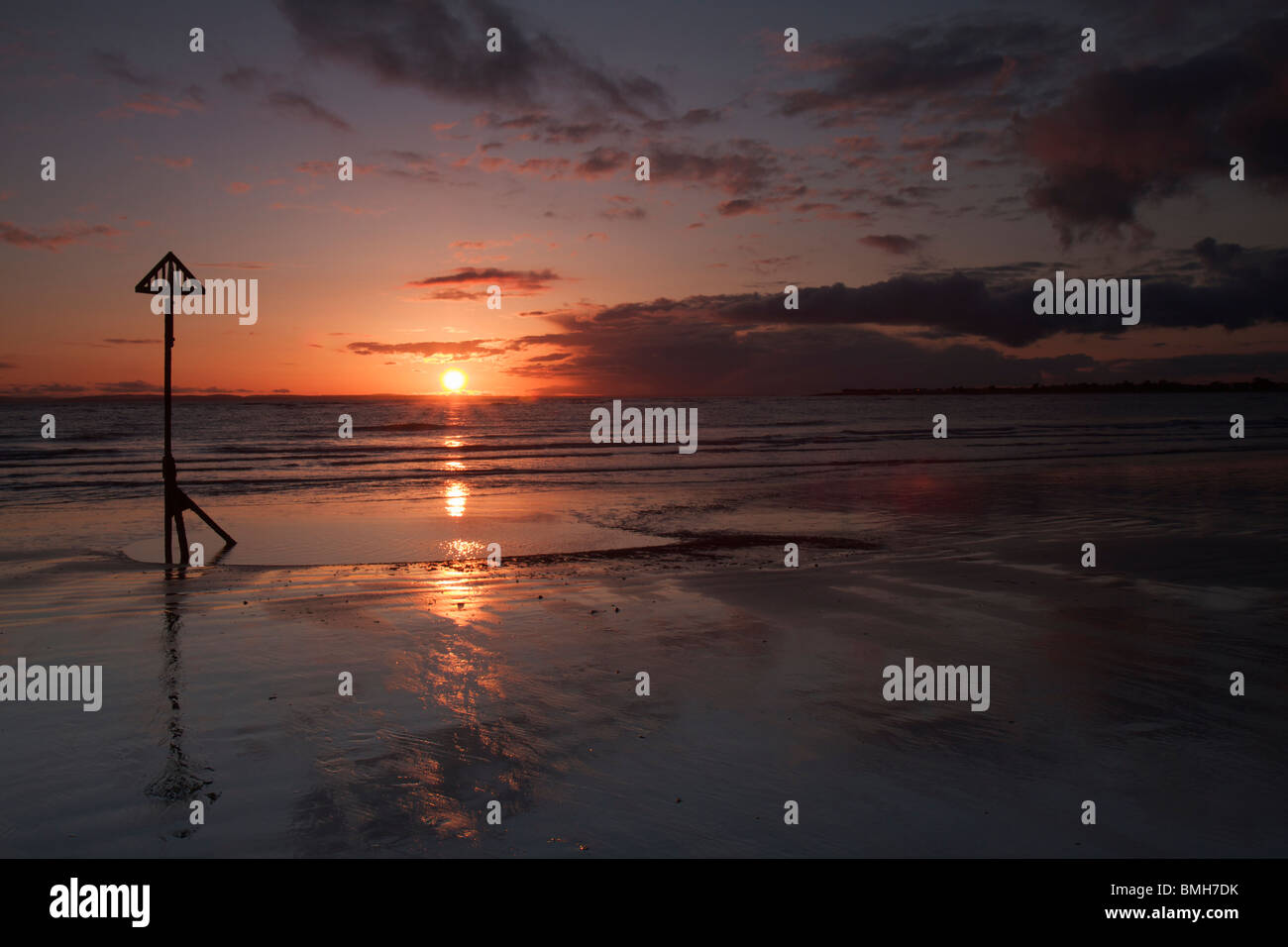 Sunset Over The Sea Reflecting In The Beach Sand At West Wittering 
