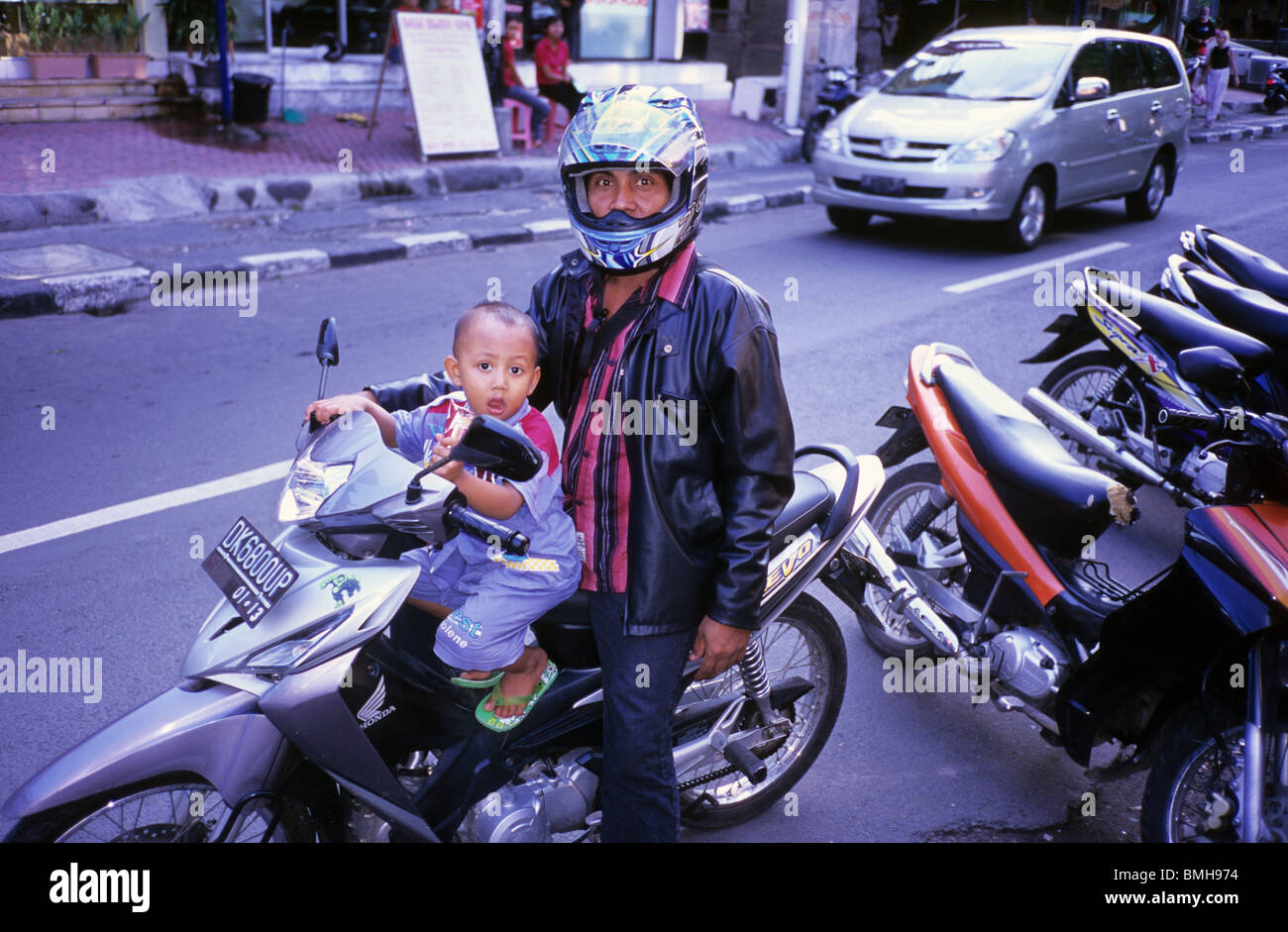 Father and young son on a motor bike in street in Bali Indonesia. Baby son sits on the petrol tank father wears leather jacket Stock Photo Alamy