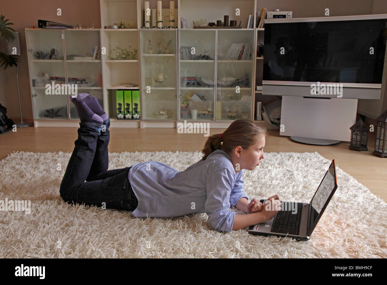 portrait of a young girl lying on the floor with her laptop Stock Photo ...