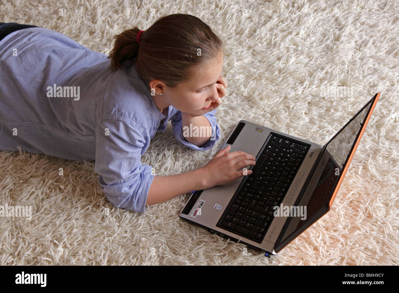 portrait of a young girl lying on the floor with her laptop Stock Photo ...