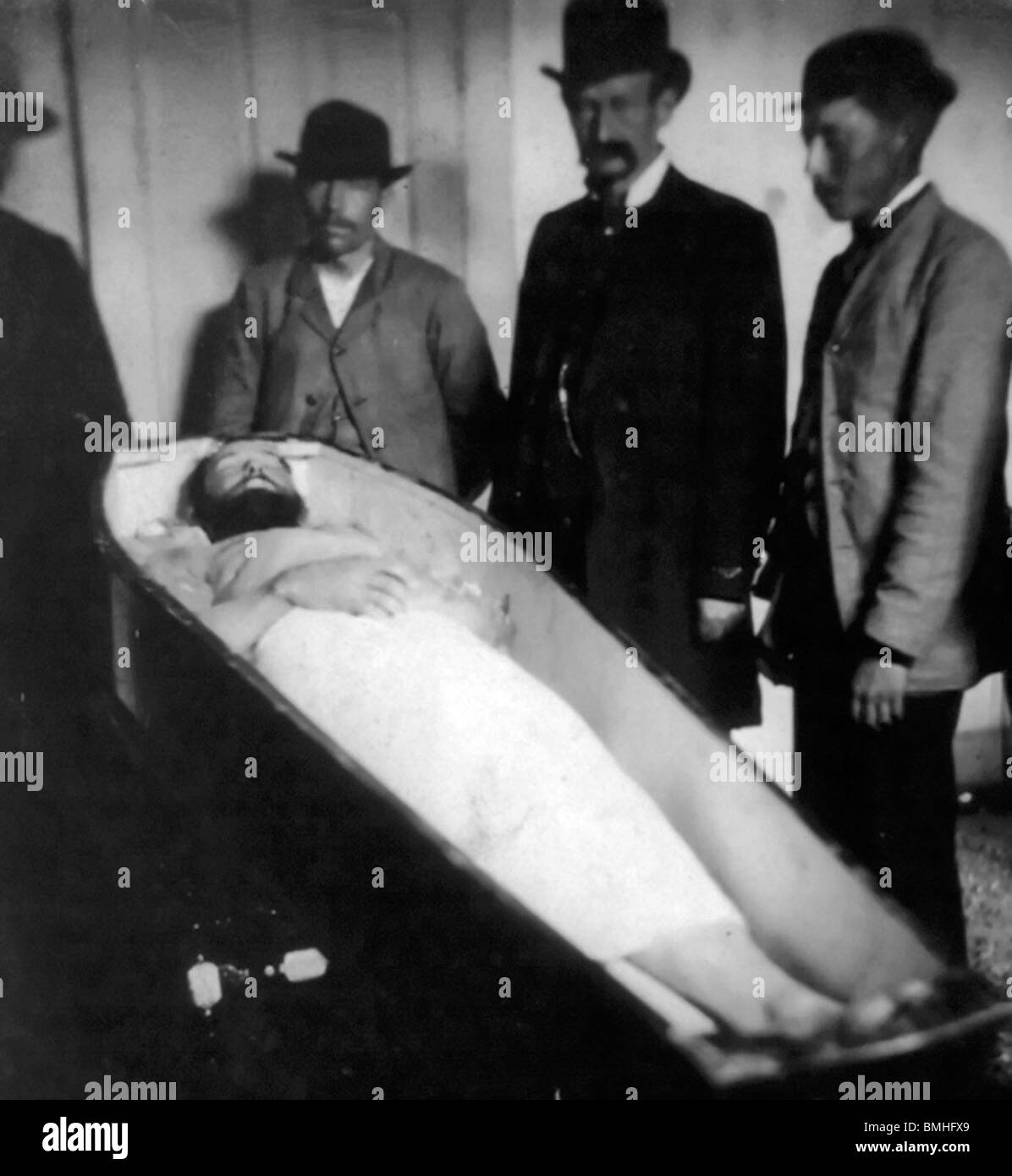 Jesse James, American Outlaw, dead in coffin body half covered with sheet 4 men standing by, 1882 Stock Photo
