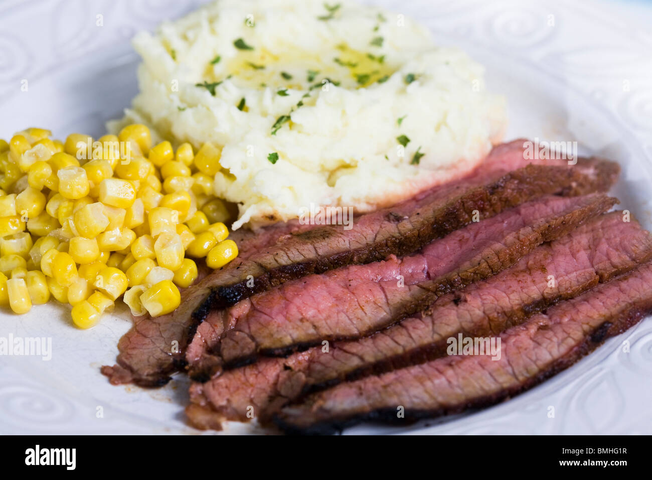Strips of London Broil steak with sides of mashed potatoes and corn Stock Photo Alamy