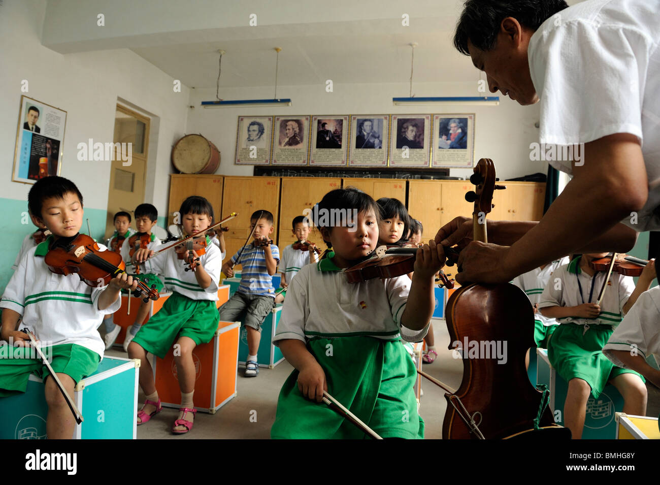 Mr. Gao Defa teaching students to play violins during a music lesson at Dawangwu primary school in Pinggu, Beijing, China. 2010 Stock Photo