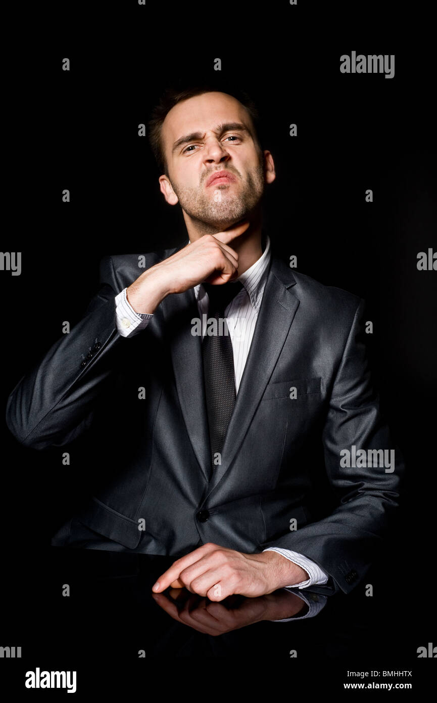 threatening young businessman behind the black desk Stock Photo