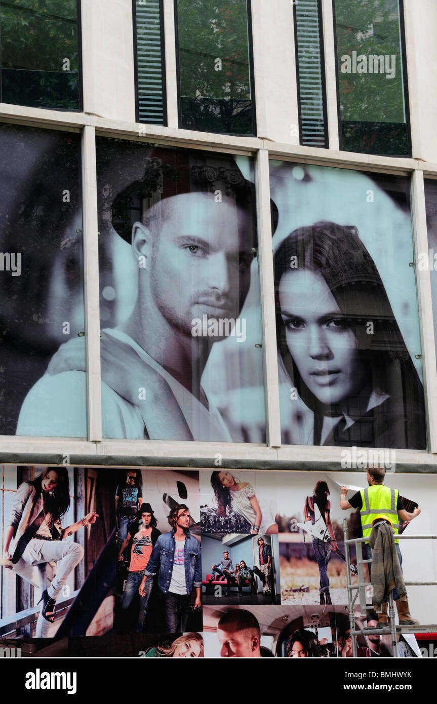 Man putting up posters billboards, Oxford Street, London, England, UK Stock Photo