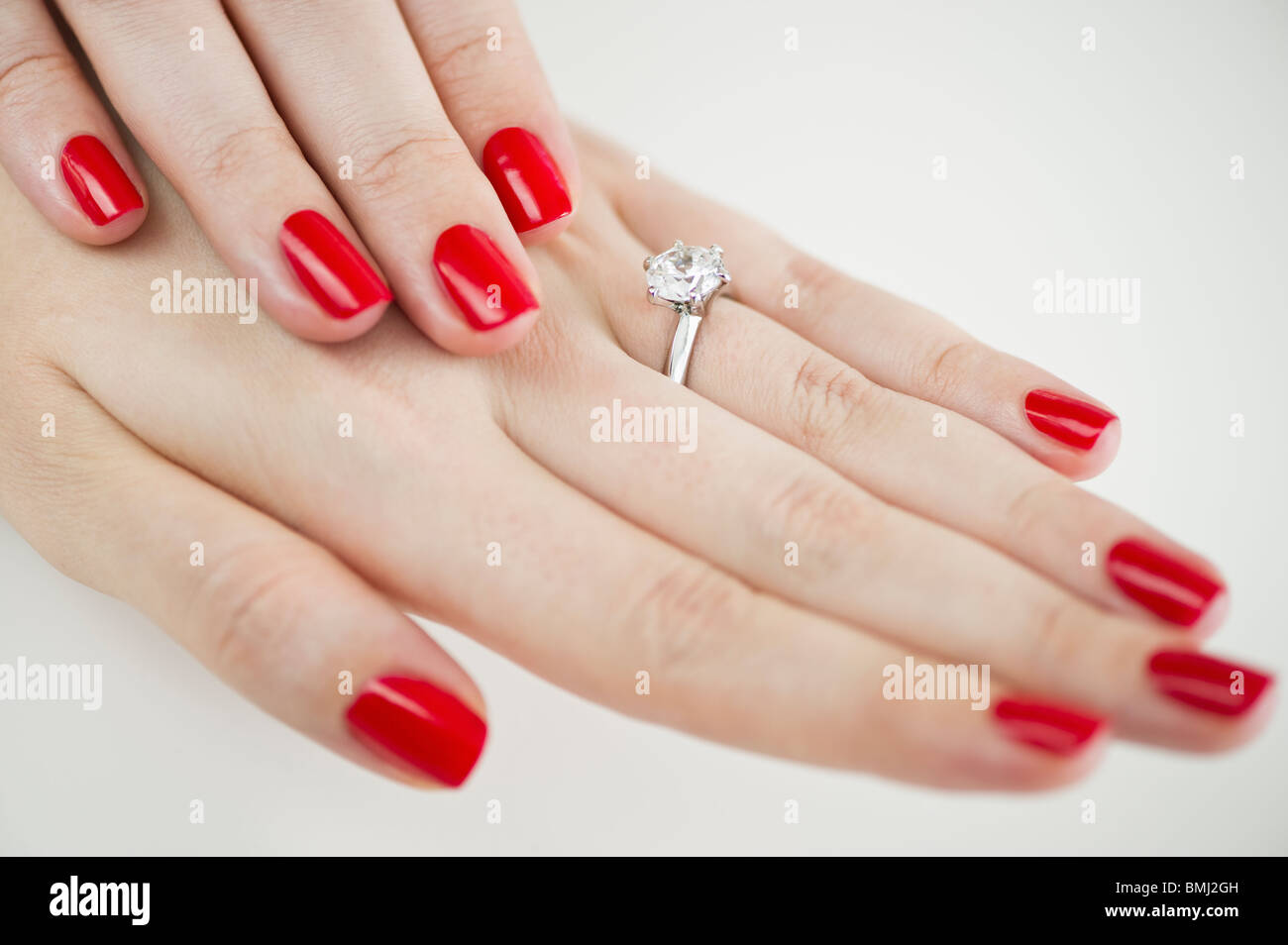 Diamond engagement ring on hands with red nail polish Stock Photo