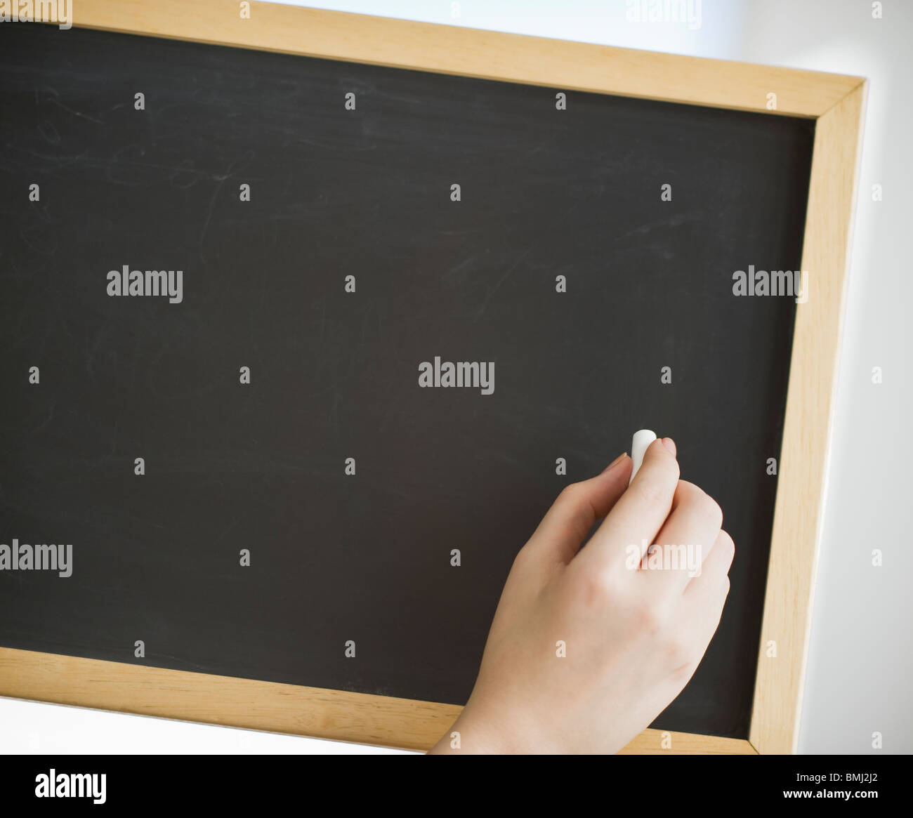 Hand holding chalk in front of blank chalkboard Stock Photo