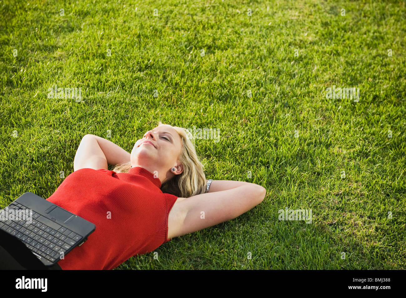 Woman lying on grass with laptop Stock Photo - Alamy