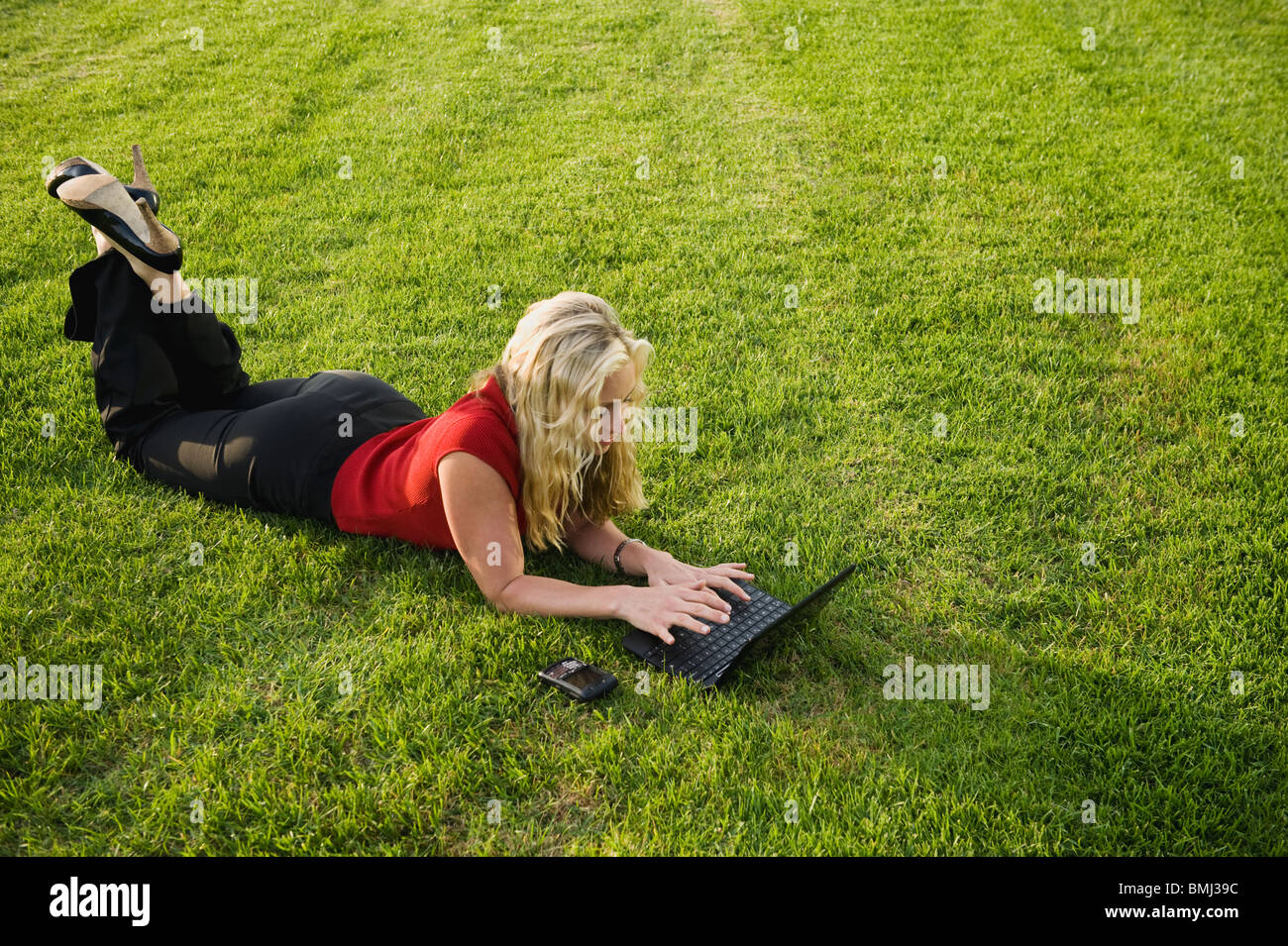 Woman working on laptop outdoors Stock Photo