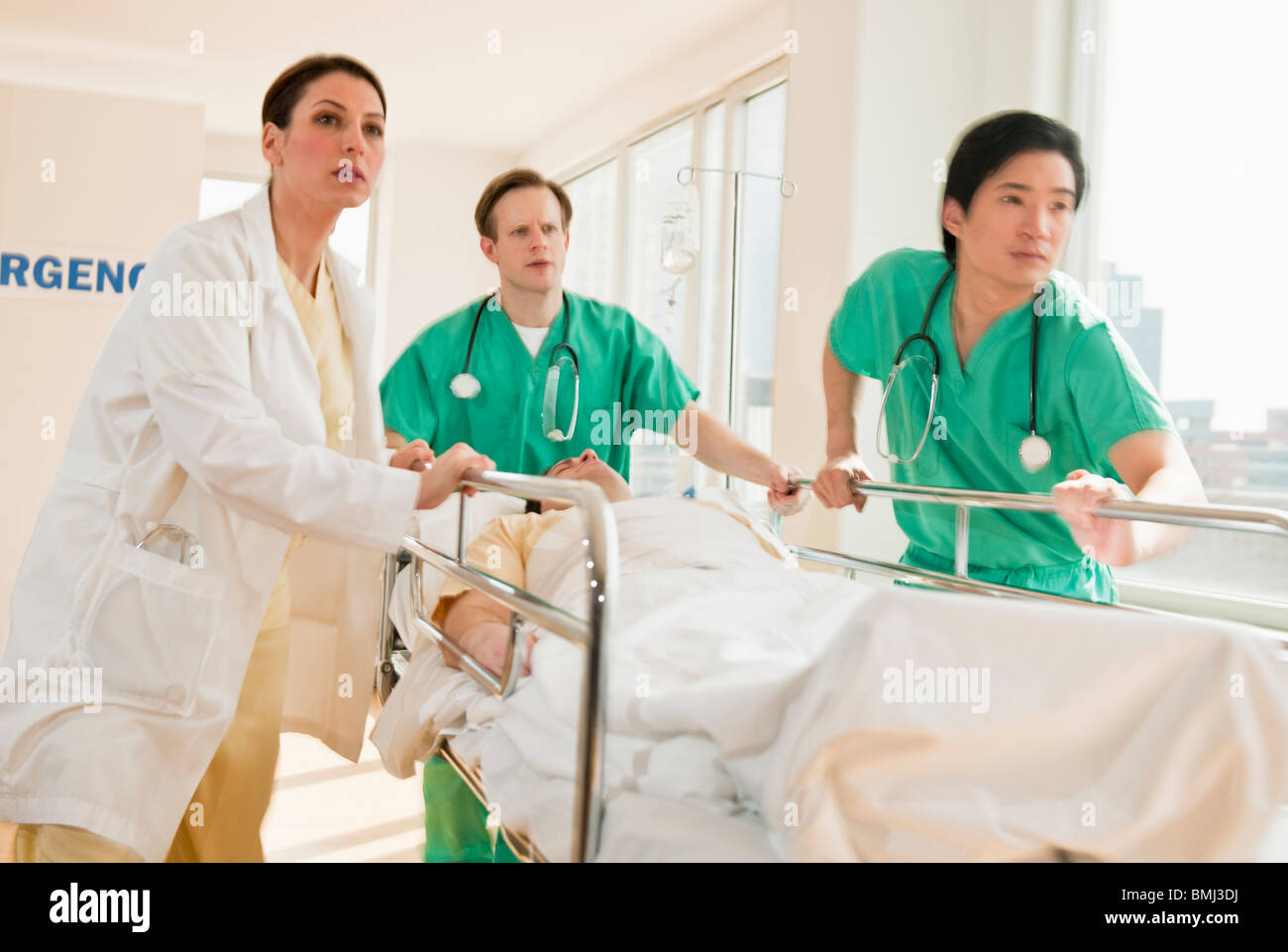 Healthcare workers pushing gurney in emergency room Stock Photo