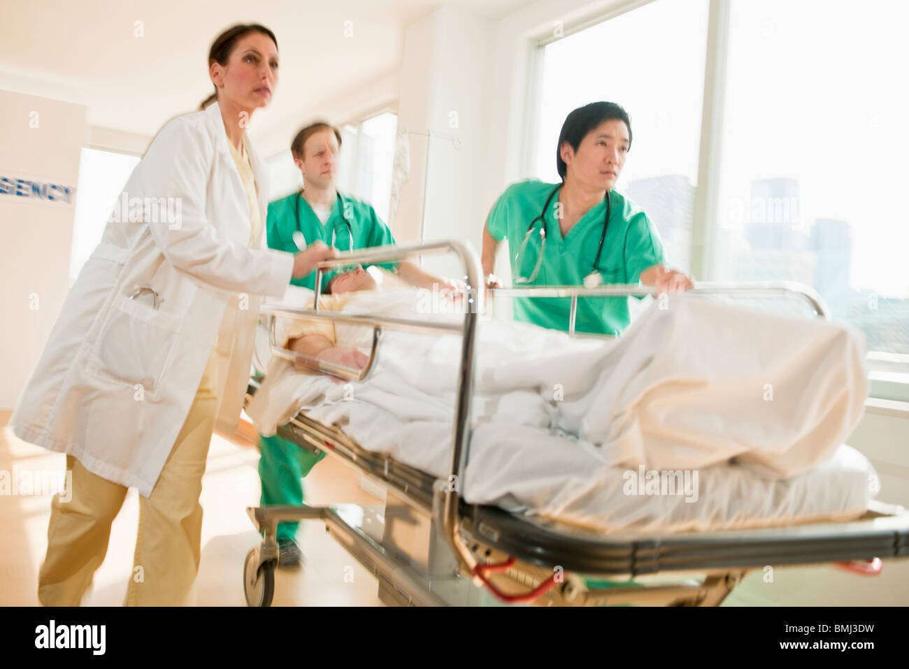 Healthcare workers pushing gurney in emergency room Stock Photo