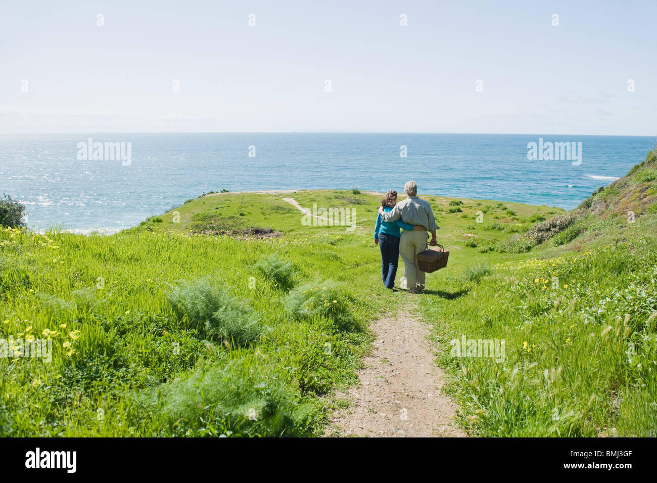 Couple carrying picnic basket to the beach Stock Photo