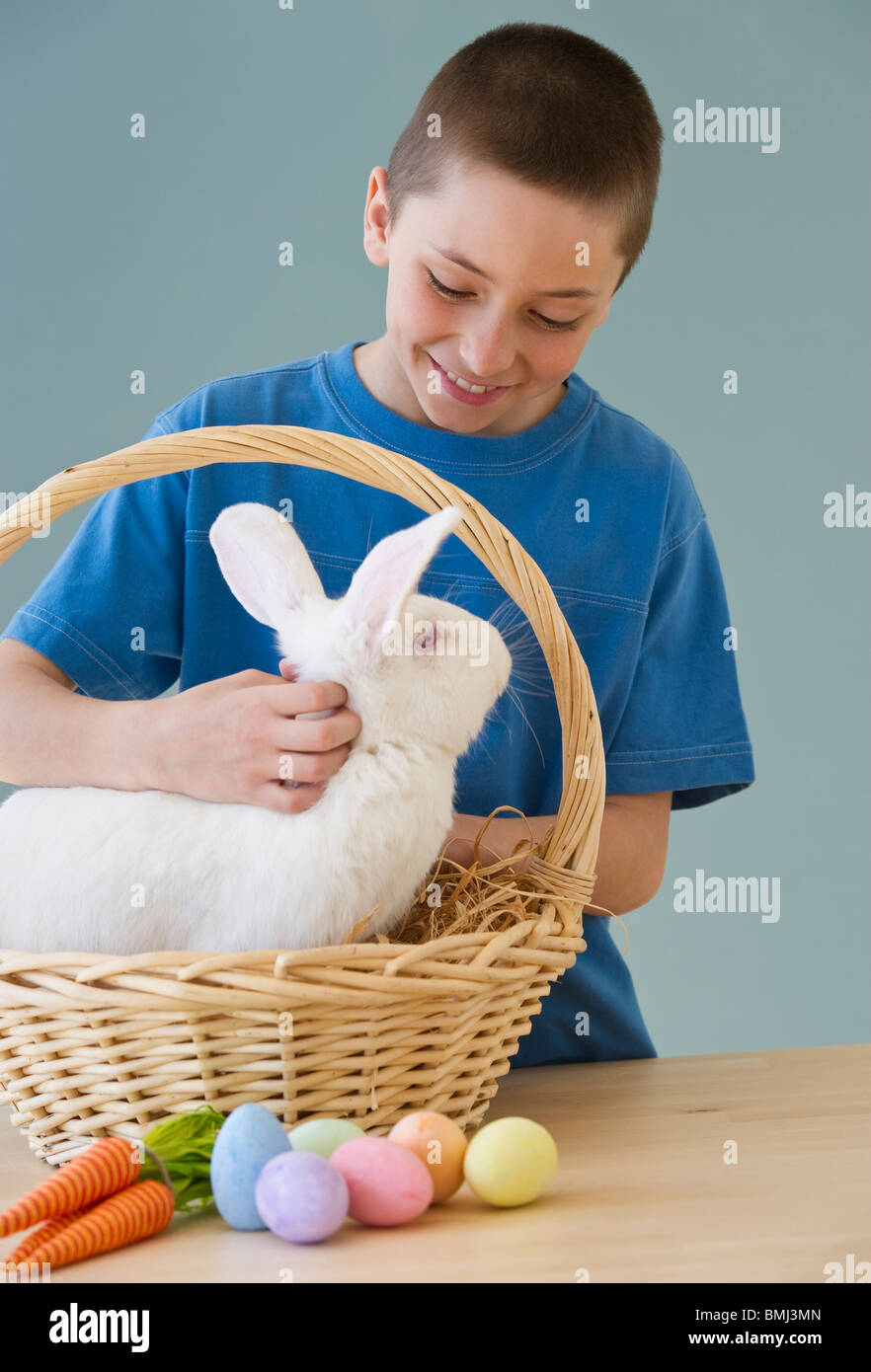 Young boy petting a rabbit in Easter basket Stock Photo